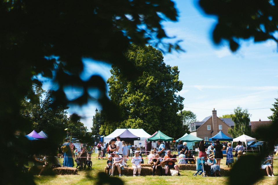 A group of people sitting around tables in a field
